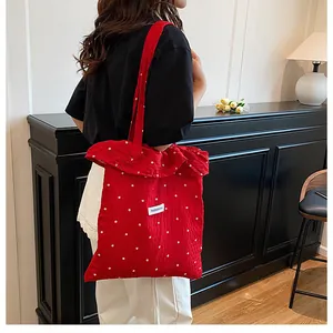 Dettaglio della borsa tote in rete floreale rossa con etichetta moda e tracolla a volant