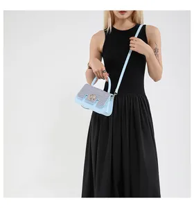 Dettaglio borsa blu e intrecciata con logo M dorato indossata con un abito nero lungo