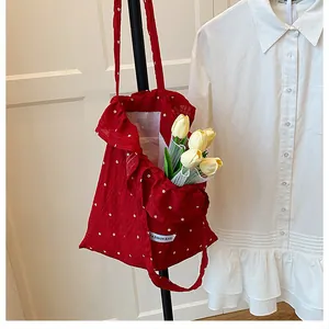 Dettaglio borsa tote in rete rossa floreale con bordi a balze ed etichetta moda