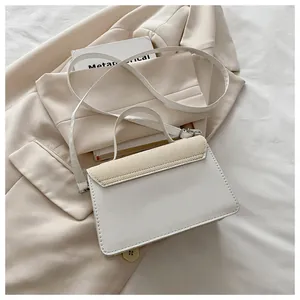 Detail van witte vierkante crossbodytas met geweven deksel en elegant handvat