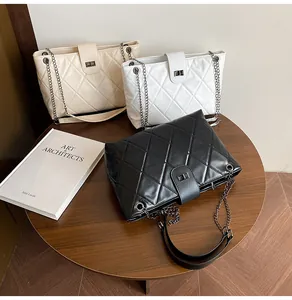 Three quilted chain bags in black, white, and cream on a wooden table set