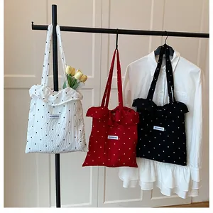 Dettaglio di borse tote in rete a pois con bordi a volant nei colori rosso, nero e bianco