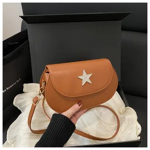 Gros plan du sac besace marron avec étoile en strass argentés dans un coffret