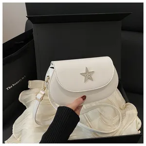 Détail du sac de selle blanc avec boucle étoile en strass et bandoulière réglable