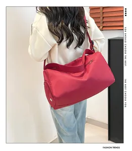 Sac de sport en nylon rouge avec bandoulière ajustable présenté de dos par un mannequin
