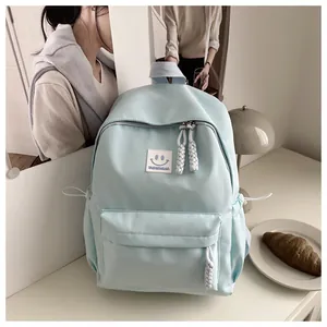 Detalle de mochila azul claro con parche de sonrisa y tiradores de cremallera trenzados