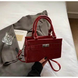 Top view of dark red crocodile embossed handbag with metal lock and handle on a blazer