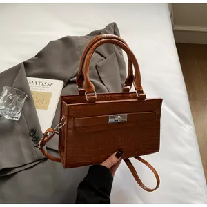 Close-up of brown crocodile texture leather bag with silver metal swivel lock and double handles