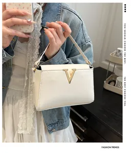 Dettaglio della borsa in ecopelle crema con elegante fibbia in metallo dorato a V