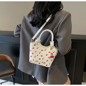 Detail of a white cherry print bucket bag with detachable strap shown on a model