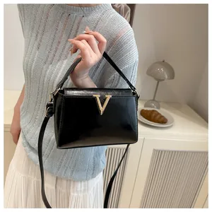 Dettaglio borsa a mano nera lucida con fibbia in metallo dorato a forma di V elegante