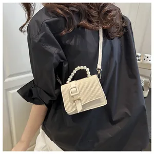 Gedetailleerd zicht op dames mini crossbody tas met parelhandvat en geweven textuur