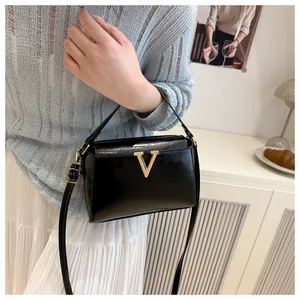 Borsa a mano chic in pelle nera lucida con logo V dorato in una scena d'interni accogliente
