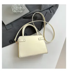 Top view of cream white structured handbag on a suit jacket with gold metal hardware