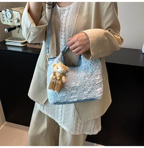 Détail du sac seau plissé bleu clair avec breloque ours dans un décor de café décontracté