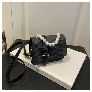 Detail van grijze tweed handtas met parelketting en zwart lederen gespband voor dames