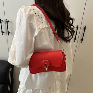 Chic red faux leather underarm bag with a bold gold buckle and minimalist square structure