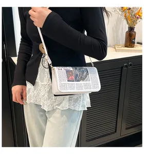 Détail du sac bandoulière blanc imprimé journal avec motif vintage et boucle en métal