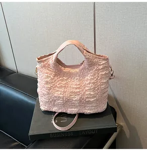Détail du sac seau rose clair avec texture plissée rose clair et crochets métalliques dorés