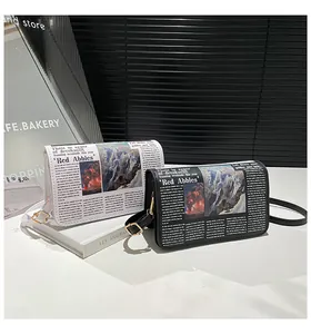 Detail van crossbodytassen met krantenprint, gouden gespen en leren schouderbanden