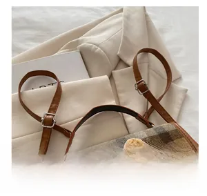 Detail of adjustable PU leather shoulder strap with metallic buckle on plaid bear bag