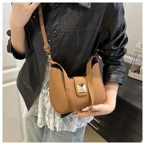 Detail of caramel brown PU leather crossbody bag with a large gold buckle on model