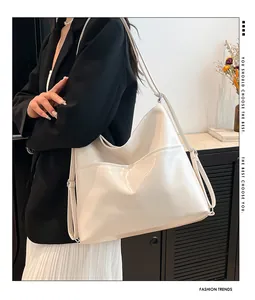 Close-up of a cream faux leather tote bag showing glossy texture and front pocket detail