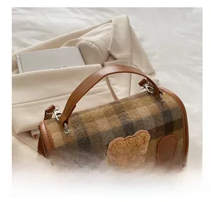Close-up of brown plaid backpack with teddy bear patch on a beige blazer background