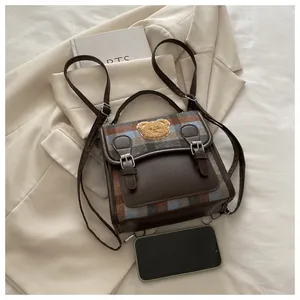Detail of vintage square backpack in dark brown PU leather with plaid fabric pattern