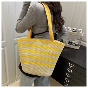 Detailed view of yellow striped straw tote bag with woven straps on a model