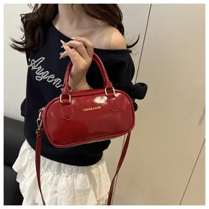Detail of red patent leather mini boston bag with gold hardware and fashion text