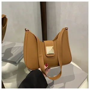 Detail of tan matte leather bag featuring curved top design and square gold metal buckle