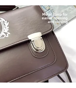 Detailed view of dark brown leather bag featuring a silver metal clasp and embroidered crest
