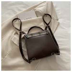 Detail of dark brown leather backpack with retro plaid flap and metal hardware detail