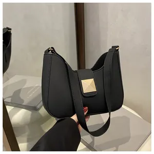 Detail view of a black matte hobo bag with a gold square clasp on a mirrored surface