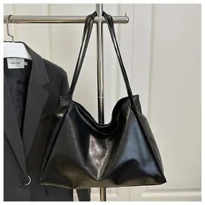Primer plano de un bolso tote de cuero PU negro brillante con textura de grano fino
