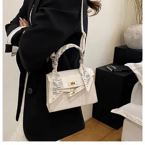 Detail of white crocodile texture handbag with silk scarf handle and golden lock