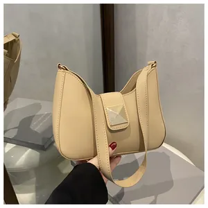 Detail of light beige crossbody bag with golden pyramid buckle and smooth matte finish