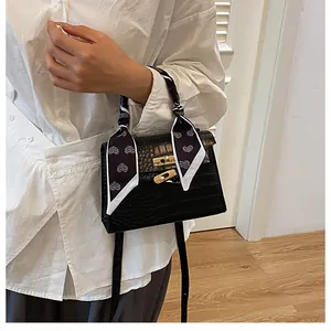 Detail of black crocodile texture bag featuring gold hardware and heart-printed scarf