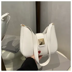 Detail view of a white PU leather shoulder bag featuring a golden pyramid stud accent