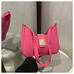 Detail of rose pink handbag featuring a large golden square rivet and smooth faux leather