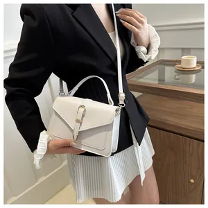 Chic white leather crossbody bag with gold buckle detail shown on a stylish model