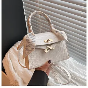 Detail of white crocodile texture handbag with gold metal twist lock and music note scarf