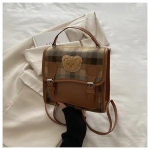 Detail of plaid retro backpack with cute bear patch and premium leather trim details