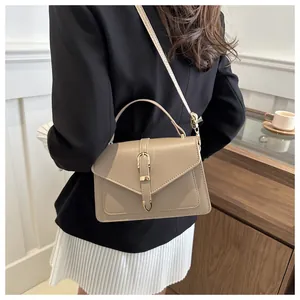 Fashionable khaki leather crossbody bag with gold buckle shown on a model