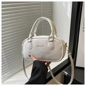 Detail of white mini crossbody bag with gold FASHION & BAGS logo and leather texture