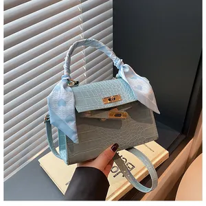 Detail of light blue crocodile embossed handbag with silk scarf handle and gold hardware