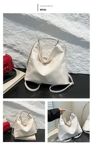 Detail of white patent leather tote bag featuring foldable front pocket and strap
