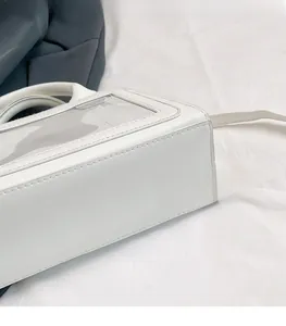 Dettaglio della borsa squadrata bianca minimalista in PVC trasparente con cuciture in pelle