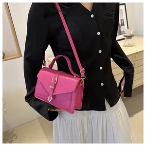 Detail of hot pink crossbody bag with gold buckle and top handle in a home setting